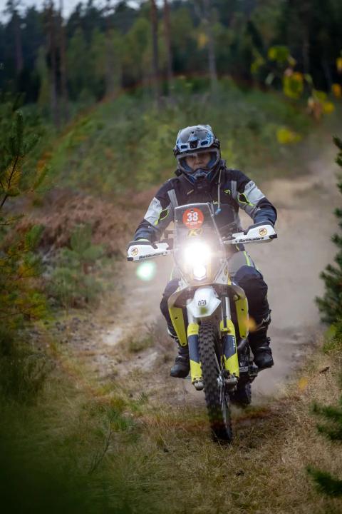 A rider with headlight on a sandy forest trail