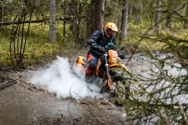Oranzi tsikliga sõitja väljub veest valge aurupilvega