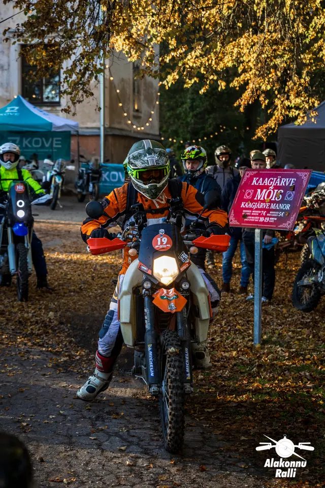 Alakonnu Ralli 2026: oranžil mootorrattal sõitja seisab hoovis inimeste ees.