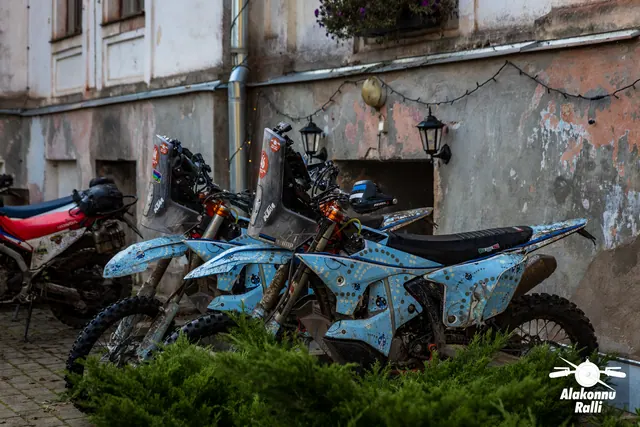 Alakonnu Ralli 2026: porised matkaenduromootorrattad pargitud vana hoone seina äärde.