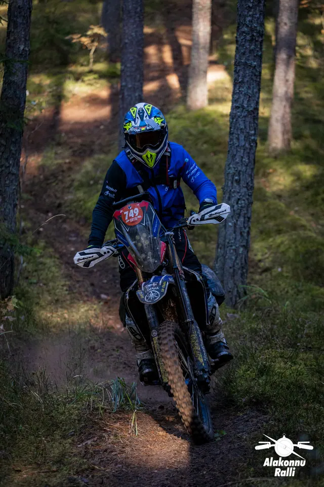 Alakonnu Ralli 2026: sinises varustuses sõitja kallutab mootorratast puude vahel.