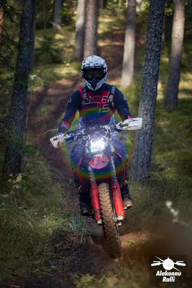 Alakonnu Ralli 2026: värvilises varustuses sõitja punasel mootorrattal puude vahel.