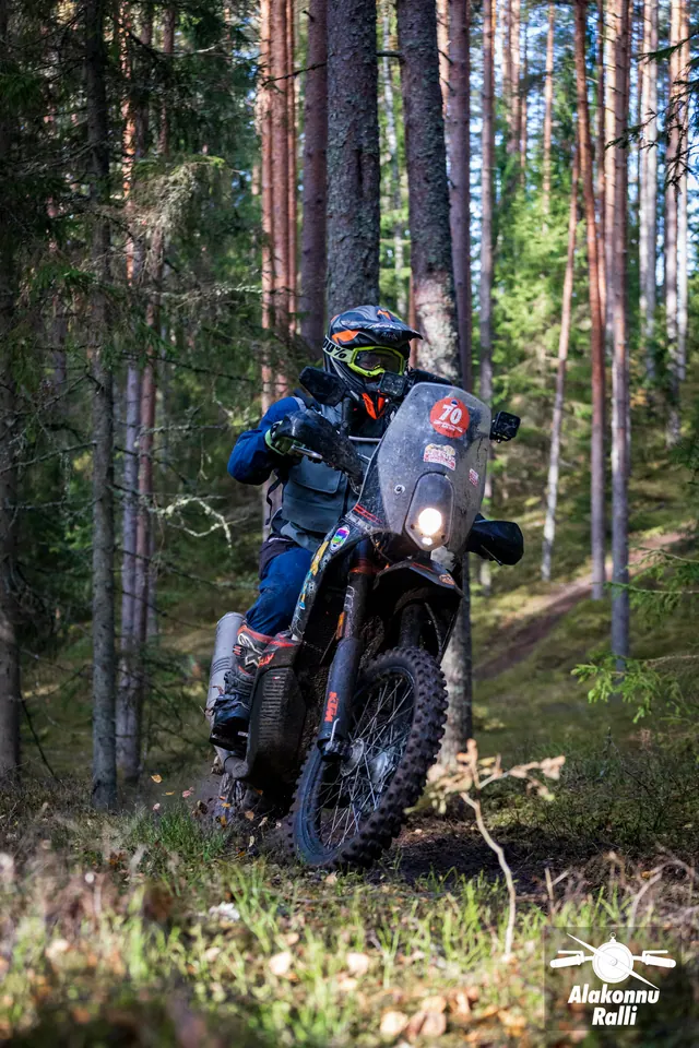 Alakonnu Ralli 2026: sinises varustuses sõitja kõrge tuuleklaasiga mootorrattal puude vahel.