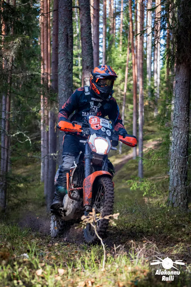 Alakonnu Ralli 2026: mootorrattur oranžil rattal möödub langenud oksast metsarajal.