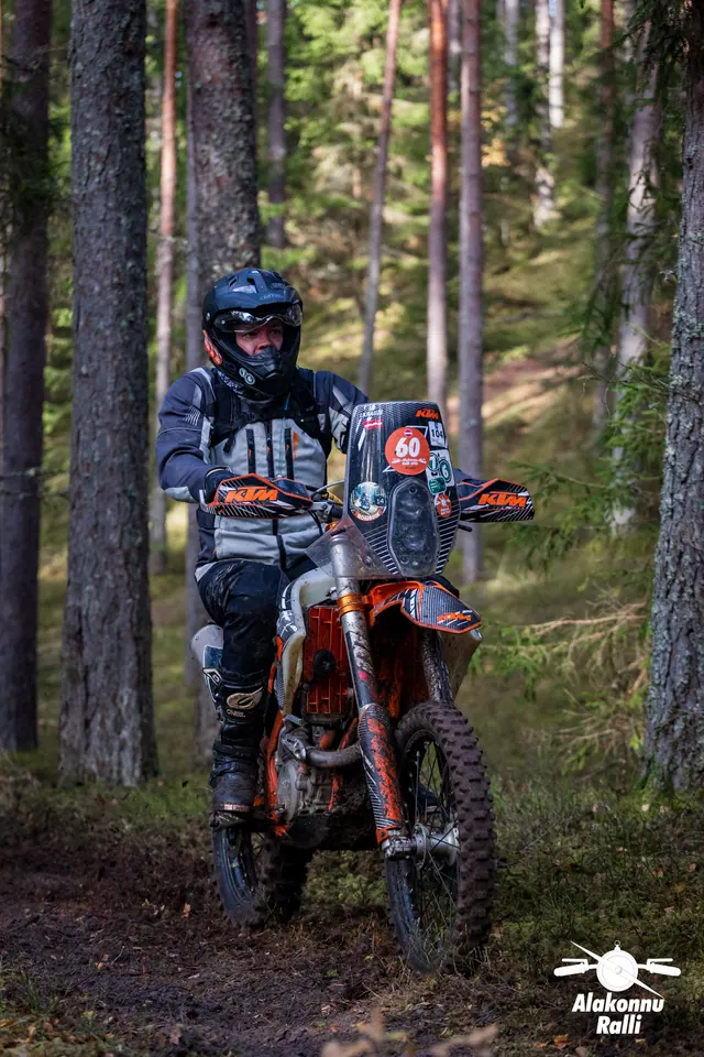 Alakonnu Ralli 2026: halli ja musta varustusega sõitja oranžil rattal läheneb metsas.