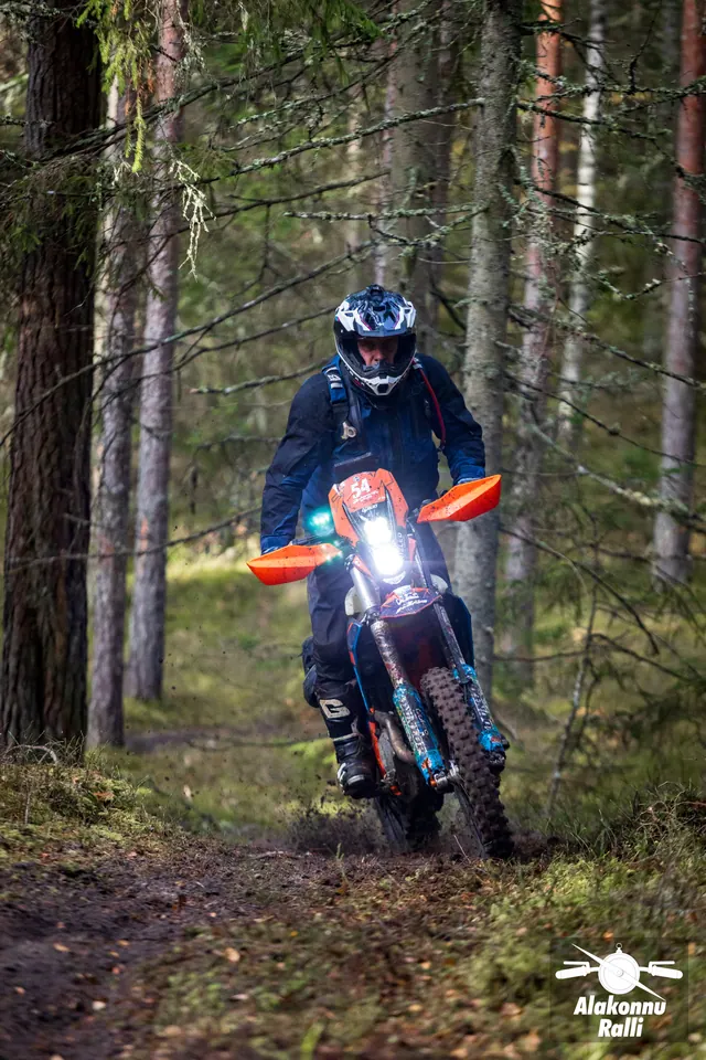 Alakonnu Ralli 2026: sinises varustuses sõitja oranžide käekaitsmetega rattal puude vahel.