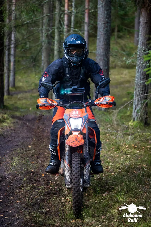 Alakonnu Ralli 2026: mustas sõiduvarustuses mootorrattur oranžil rattal kitsal metsarajal.