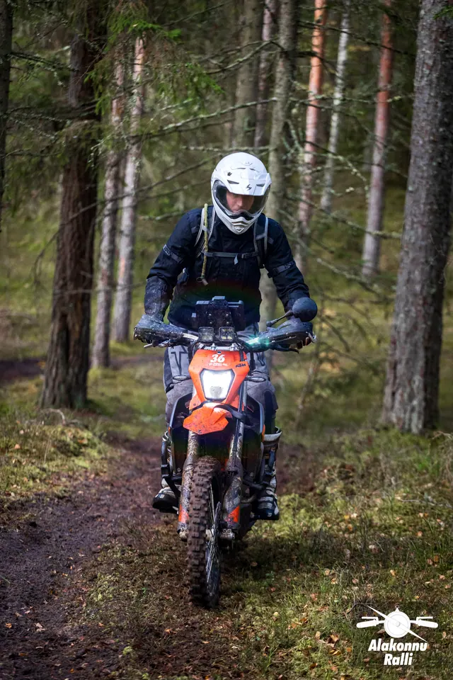 Alakonnu Ralli 2026: valge kiivriga sõitja oranžil rattal läheneb puude vahel.