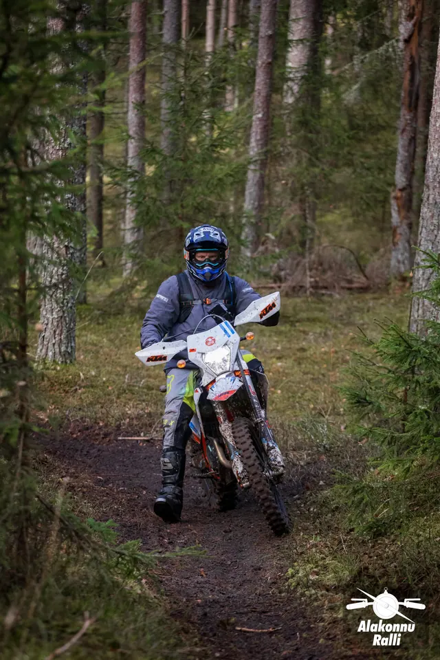 Alakonnu Ralli 2026: sõitja heledal mootorrattal hoiab jalga väljas metsakurvis.