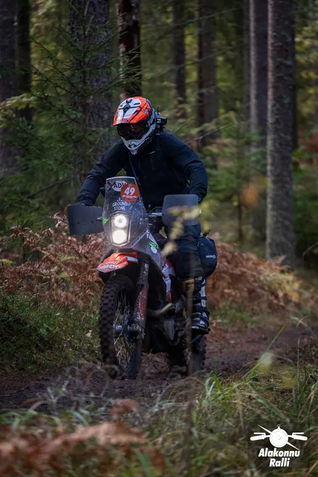 Alakonnu Ralli 2026: oranži kiivriga sõitja matkaenduromootorrattal läheneb metsas.