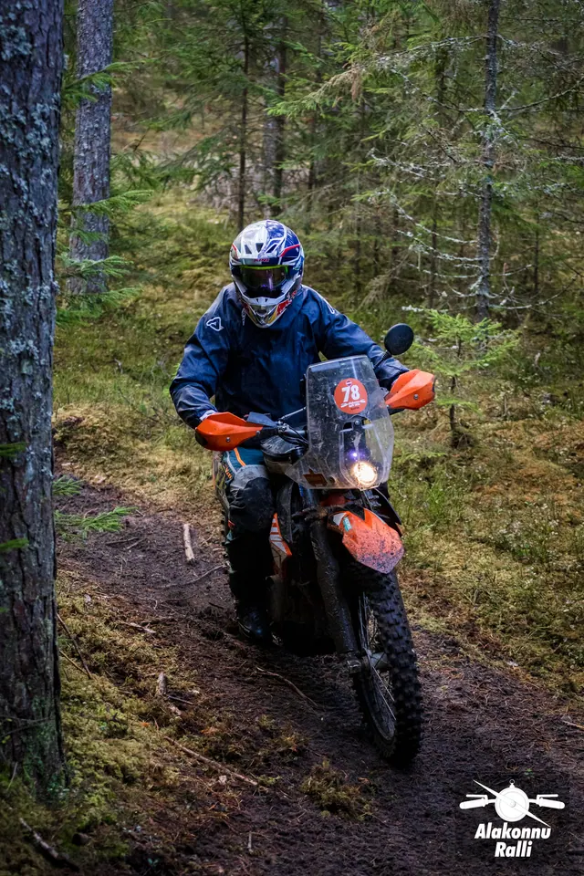 Alakonnu Ralli 2026: sinise jakiga sõitja oranžil mootorrattal kitsas metsakurvis.