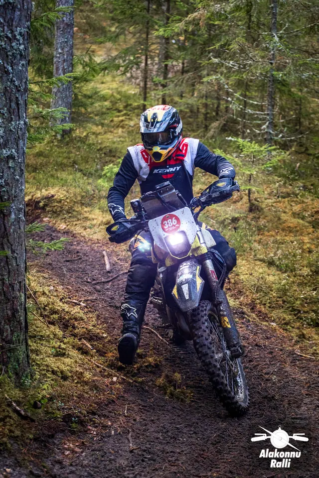 Alakonnu Ralli 2026: sõitja heledal enduromootorrattal hoiab jalga väljas metsakurvis.