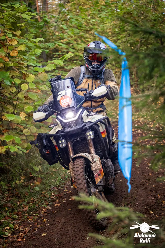 Alakonnu Ralli 2026: pruunis varustuses sõitja sõidab sinise rajatähise kõrval.