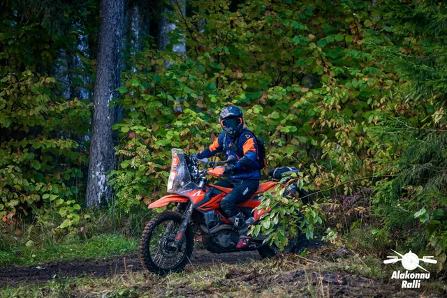Alakonnu Ralli 2026: sinise ja oranži varustusega sõitja oranžil rattal metsas külgvaates.