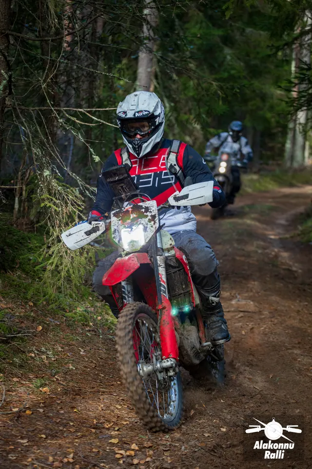 Alakonnu Ralli 2026: punase ja musta varustusega mootorrattur, teine sõitja tagapool metsateel.