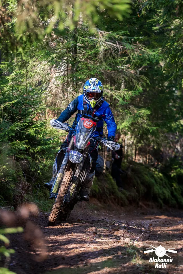 Alakonnu Rally 2026: a motorcyclist in blue riding gear leans on a narrow forest trail.