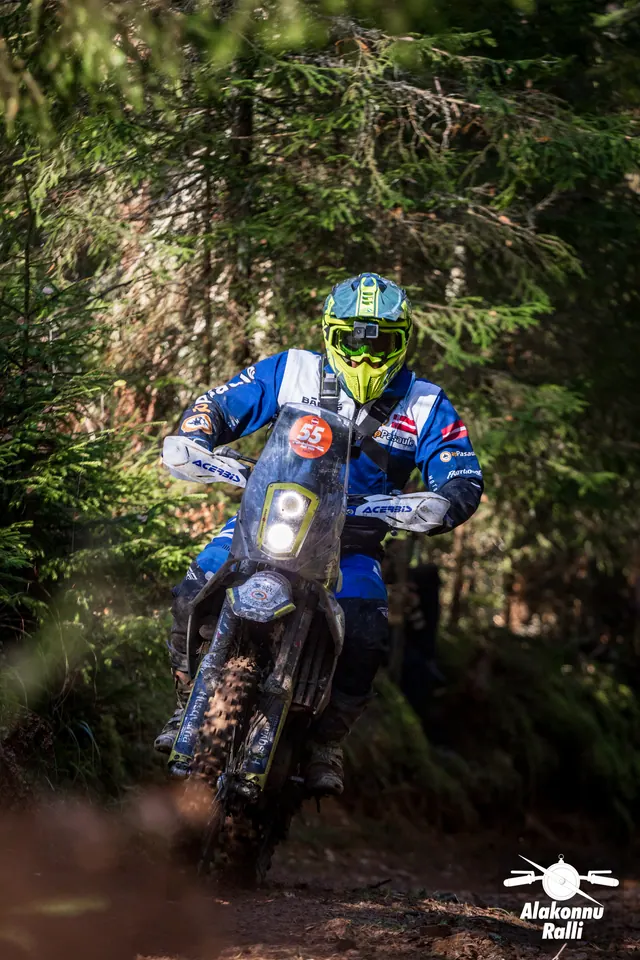 Alakonnu Rally 2026: a rider in a yellow helmet and blue and white gear at a forest bend.