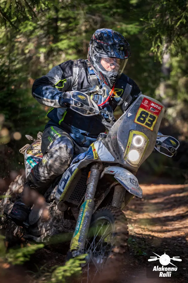 Alakonnu Rally 2026: close view of a muddy motorcycle and rider at a forest trail bend.
