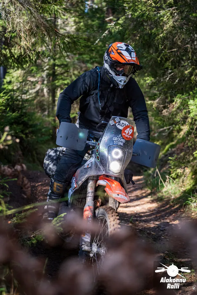 Alakonnu Rally 2026: a rider in an orange helmet stands on the footpegs of an adventure motorcycle.