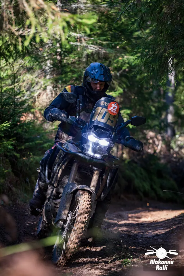 Alakonnu Ralli 2026: tumedas varustuses sõitja kallutab musta matkaenduromootorratast kurvis.