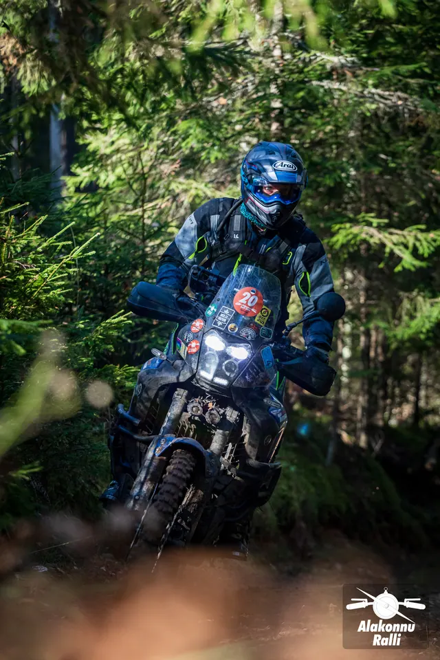 Alakonnu Ralli 2026: sinise kiivriga sõitja kallutab tumedat matkaenduromootorratast metsas.