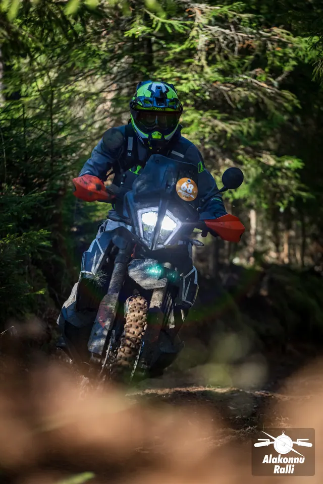 Alakonnu Ralli 2026: erksa kiivriga sõitja tumedal matkaenduromootorrattal kuuskede vahel.