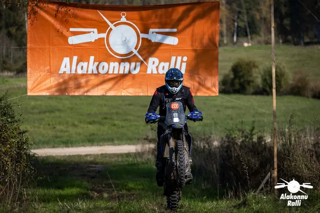 Alakonnu Ralli 2026: sinise kiivriga sõitja sinisel mootorrattal oranži rallibänneri ees.