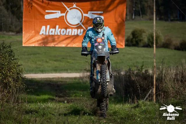 Alakonnu Ralli 2026: sinises sõiduvarustuses osaleja tõstab mootorratta esiratta rohurajal õhku.