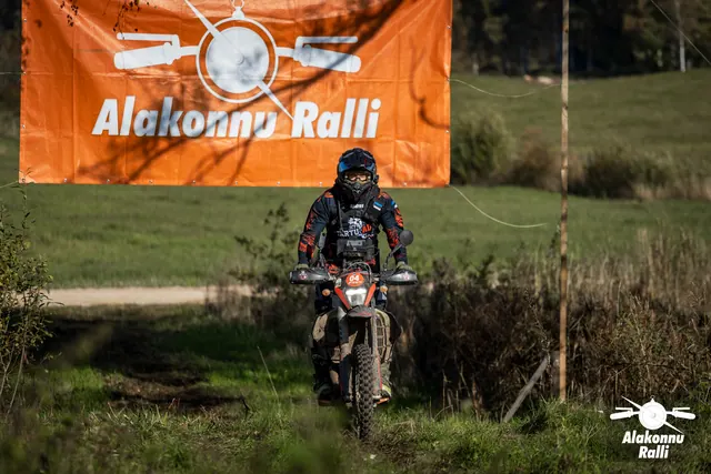 Alakonnu Ralli 2026: tumedas sõiduvarustuses osaleja sõidab mootorrattal läbi rohelise rajarööpa.