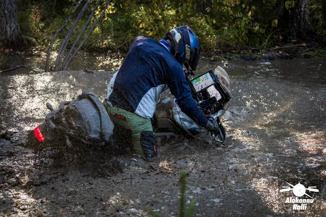 Alakonnu Rally 2026: a participant in a blue top bends over the motorcycle's handlebars in the flooded track.