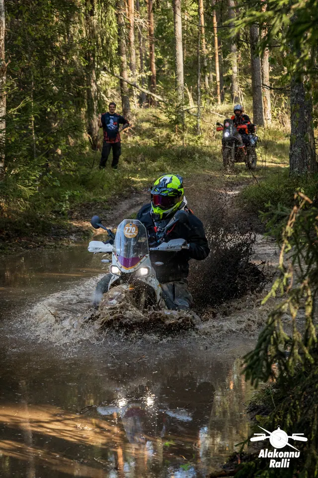 Alakonnu Ralli 2026: kollase ja musta kiivriga sõitja läheneb läbi laia metsaraja veetakistuse.
