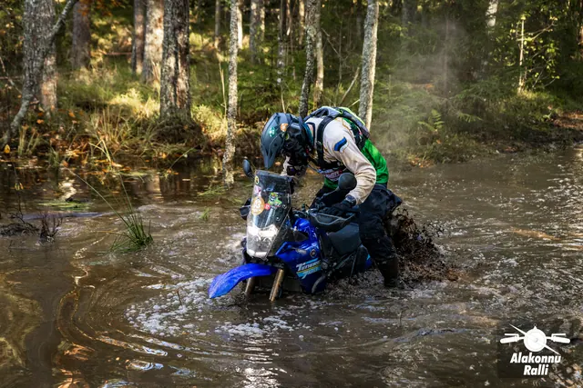 Alakonnu Ralli 2026: sõitja kummardub sinise mootorratta juhtraua kohale metsaraja veetakistuses.