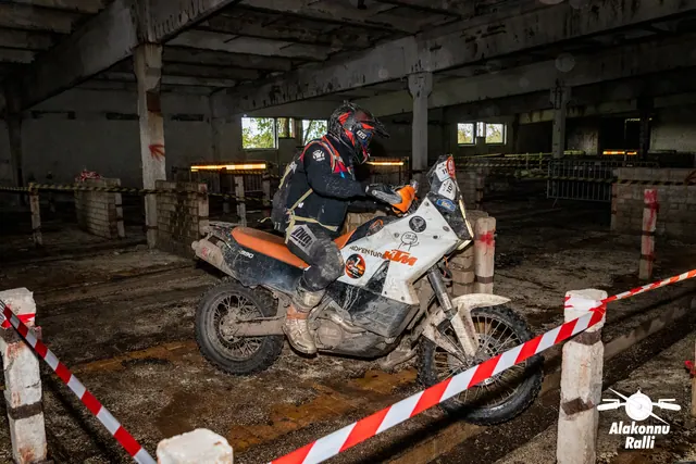 Alakonnu Ralli 2026: sõitja juhib valget ja oranži mootorratast hoones punavalge lindiga piiratud rajal.