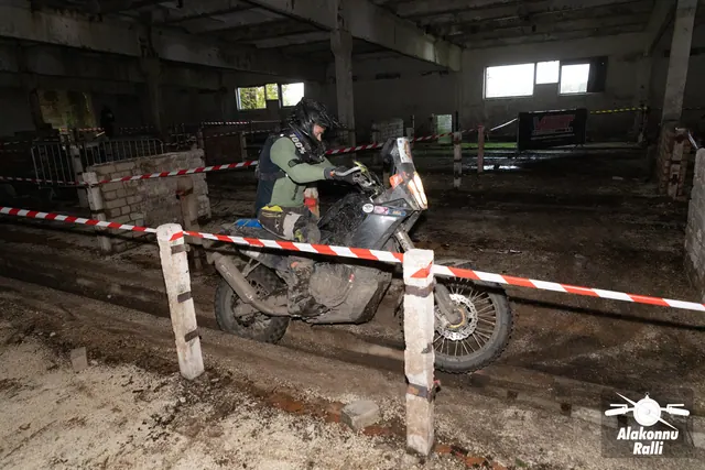 Alakonnu Ralli 2026: roheliste varrukatega sõitja liigub tumedal mootorrattal hoones mööda punavalge lindiga piiratud rada.