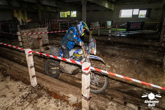 Alakonnu Ralli 2026: sinises sõiduvarustuses osaleja juhib valget mootorratast hoones mööda kitsast rajakoridori.
