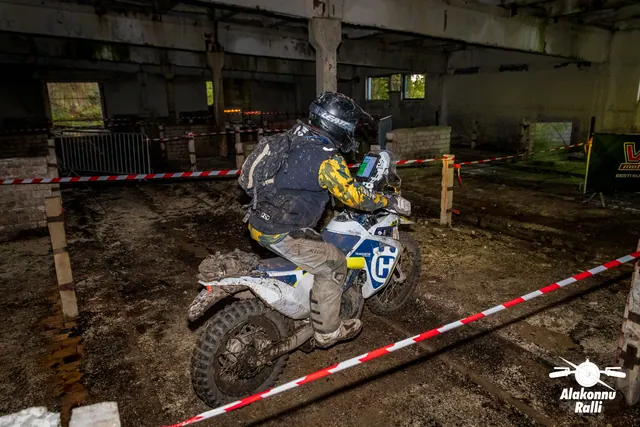 Alakonnu Ralli 2026: tumedas sõiduvarustuses osaleja liigub valgel mootorrattal hoones rajalintide vahel.