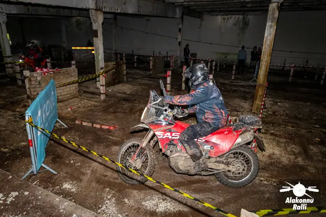 Alakonnu Ralli 2026: tumedas sõiduvarustuses osaleja pöörab punast mootorratast hoones kollase ja musta rajalindi taga.