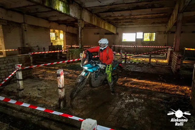 Alakonnu Ralli 2026: valge kiivriga ja oranži sõidusärgiga osaleja juhib roheka mootorratta hoones ümber rajaposti.