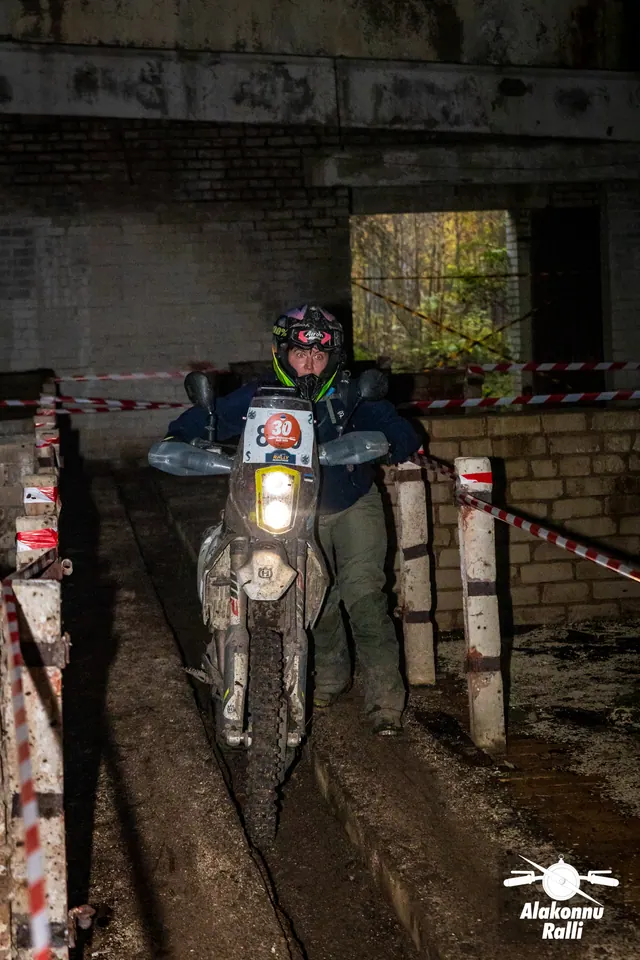 Alakonnu Ralli 2026: sõitja läheneb hoone kitsas rajakoridoris suure põleva esitulega mootorrattal.