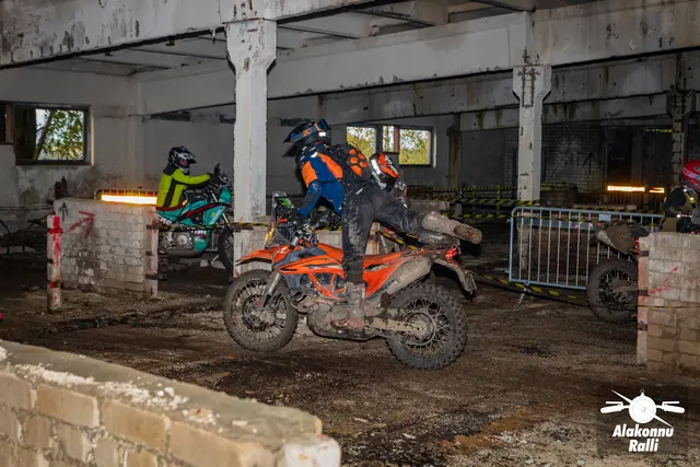 Alakonnu Ralli 2026: oranžil mootorrattal sõitja liigub hoones metallpiirde ja madalate müüride vahel, teine rattur taga.