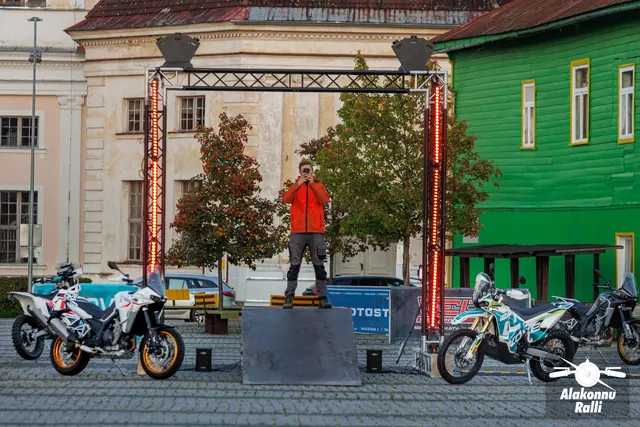 An organizer beneath the start gate beside motorcycles – Alakonnu Rally 2026, start and SS1
