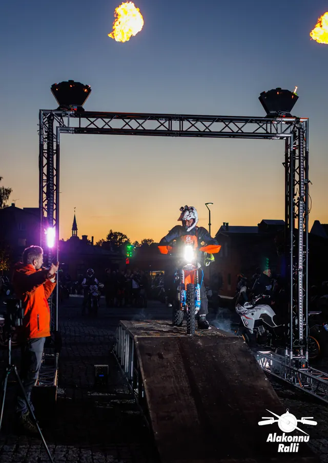 Mootorrattur valgustatud stardivärava all, korraldajad rambi kõrval – Alakonnu Ralli 2026, start ja SS1