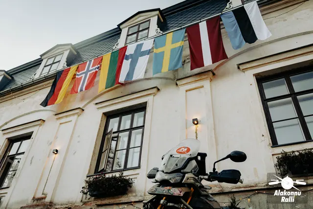 A building decorated with national flags beside rally motorcycles – Alakonnu Rally 2026, SS2 · SS3